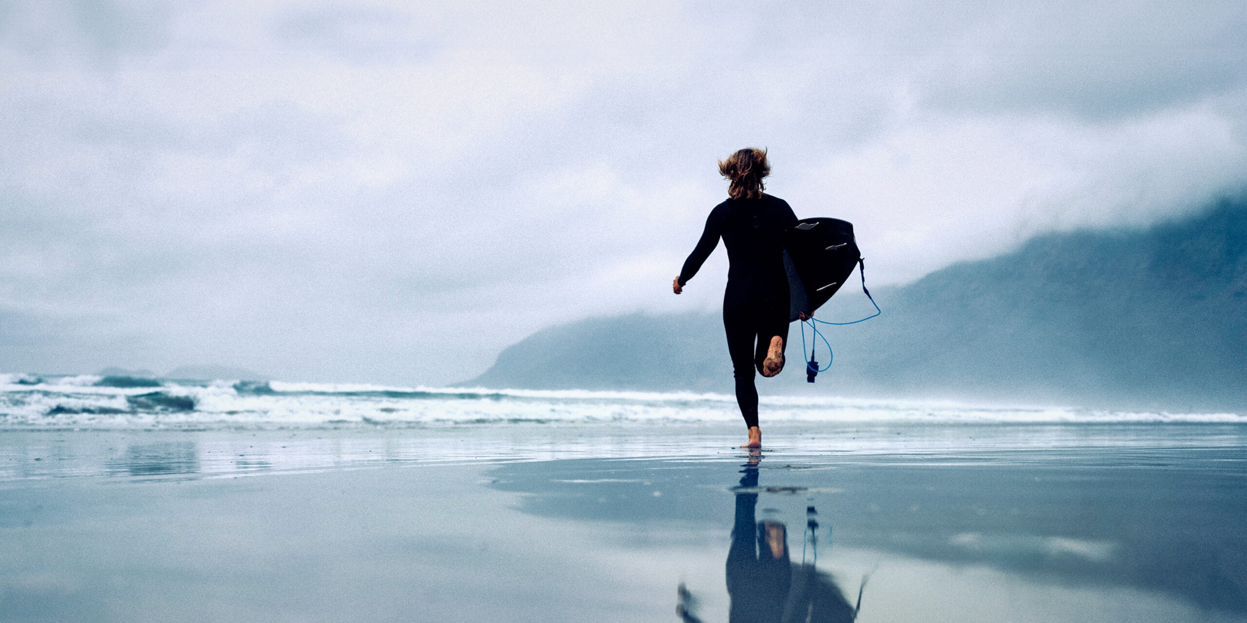 <p>Surfer woman running with surfboard in Lanzarote Canary Islands, Famara beach</p>