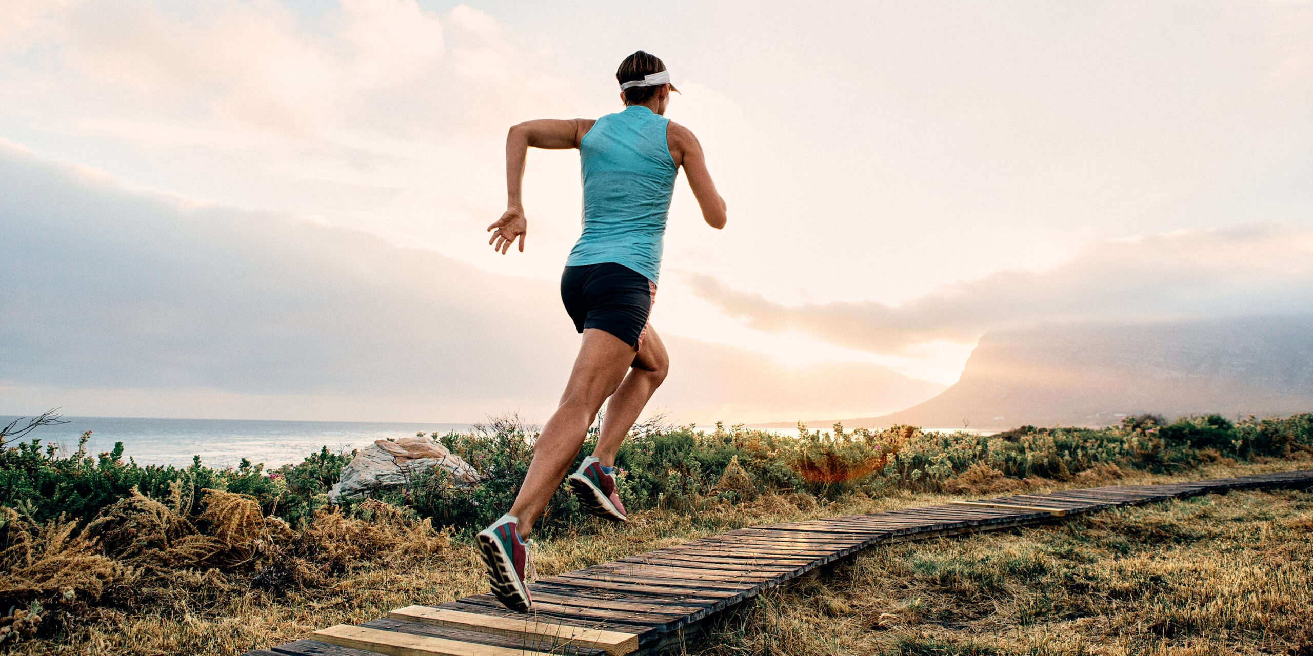 <p>Female woman enjoys her run along a coastal path into the sunset</p>